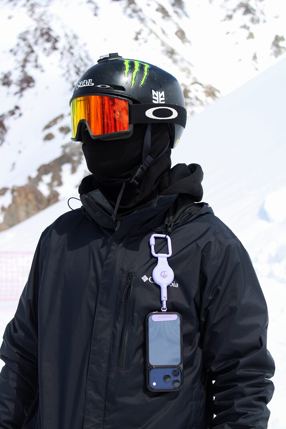 Snowboarder in a black jacket with a Lavender ClutchLoop holding their phone on the chest
